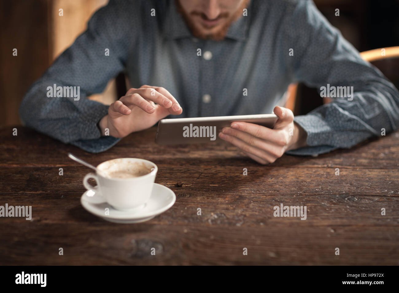 Giovane uomo utilizzando uno schermo tattile digitale compressa su una tavola di legno, mani vicino fino Foto Stock