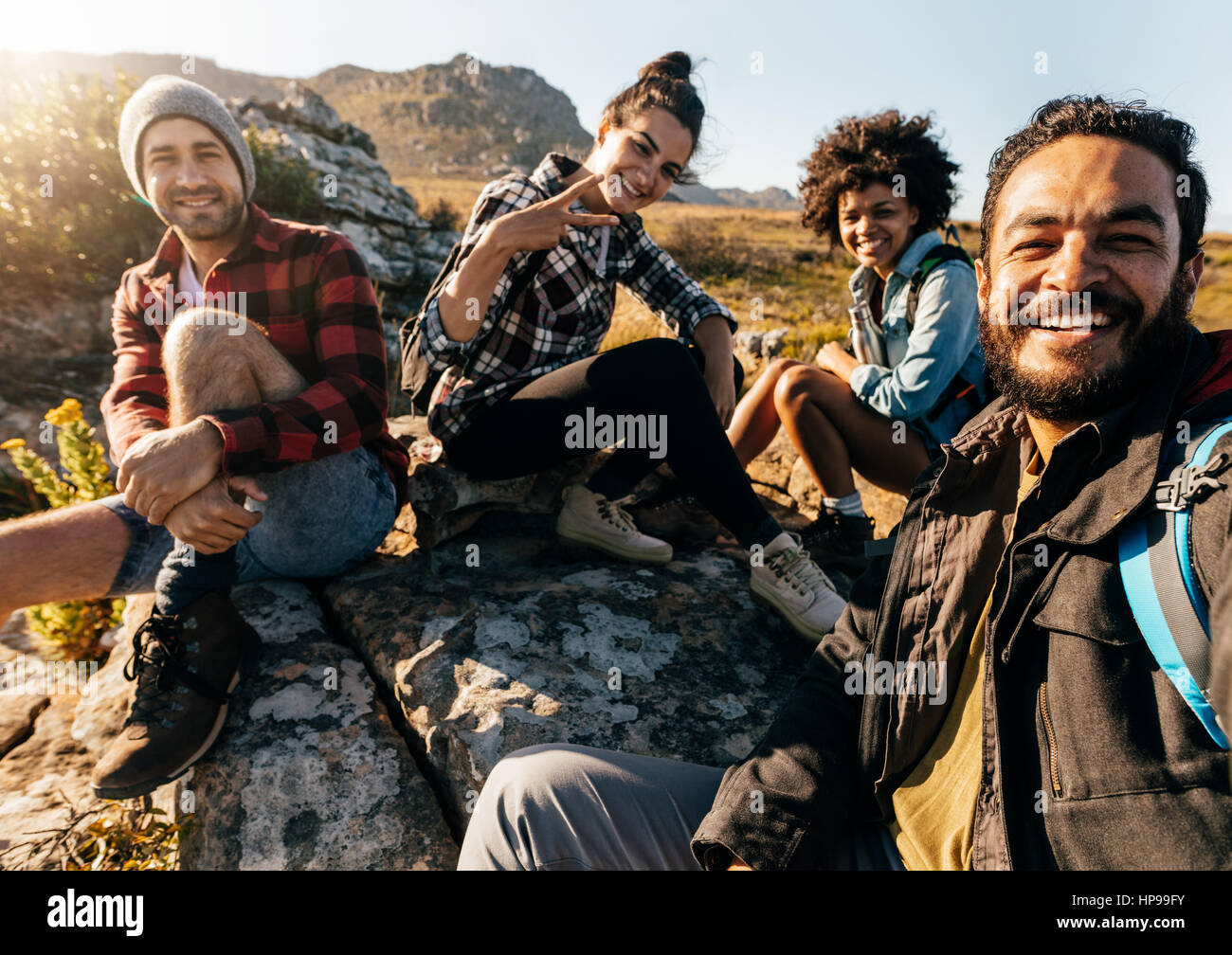 Gruppo di amici in appoggio sulla montagna mentre escursionismo. Gli escursionisti rilassante e tenendo selfie. Foto Stock