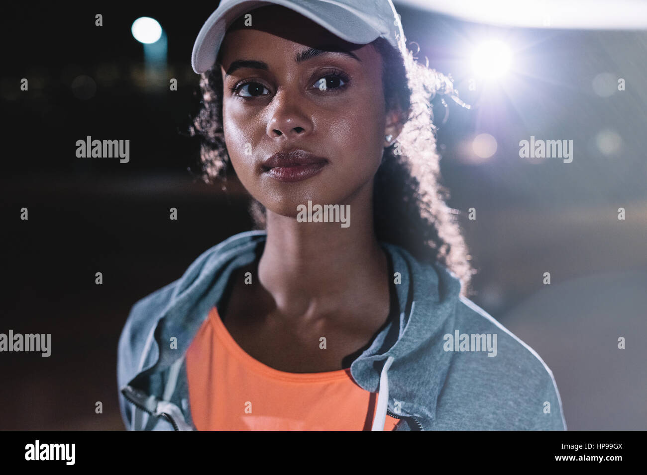Immagine ravvicinata di donna fitness nella città di notte. Bellissima femmina runner guardando lontano. Foto Stock