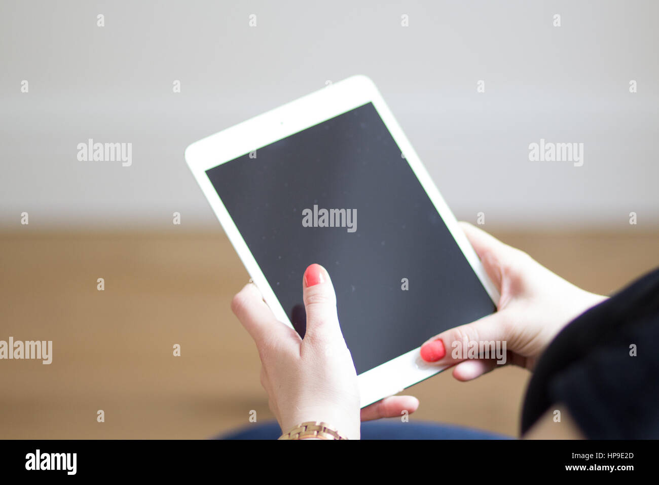 Una donna caucasica con chiodi rossi mantiene un iPad bianco Foto Stock