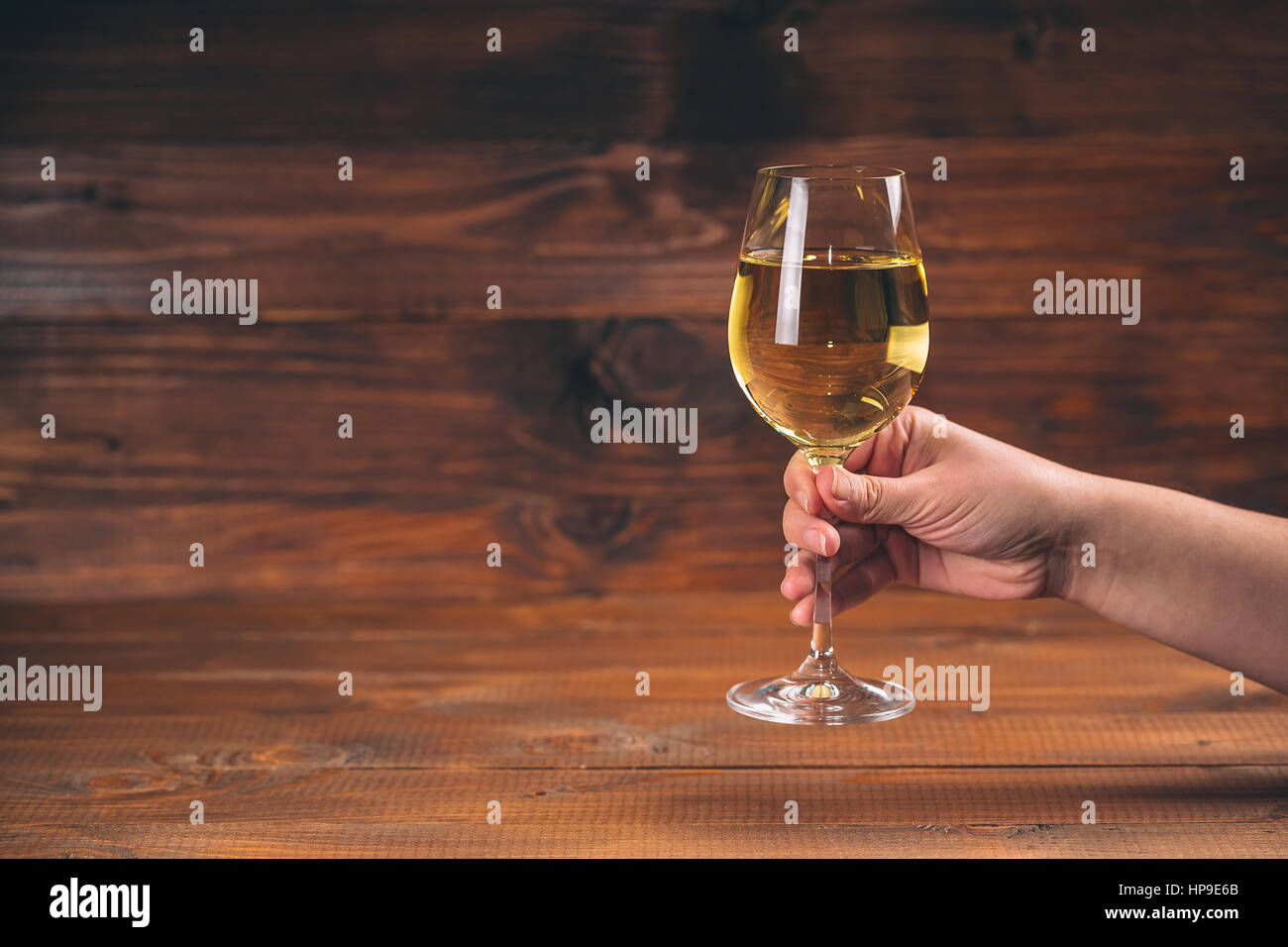 Donna mano tifo con bicchieri di vino bianco contro lo sfondo di legno Foto Stock