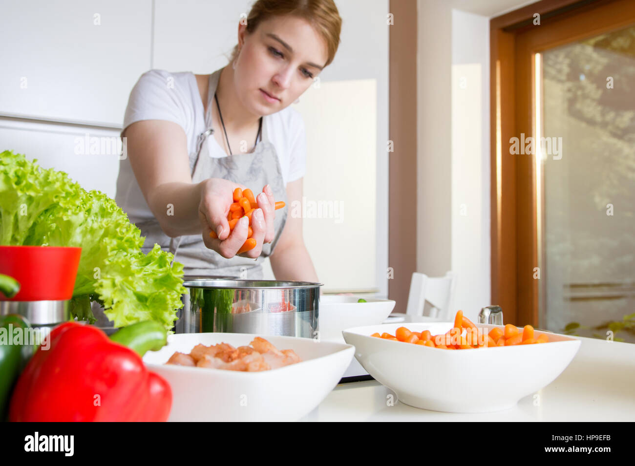 Donna usa le carote per preparare un pasto. Il concepimento di una sana alimentazione. Foto Stock