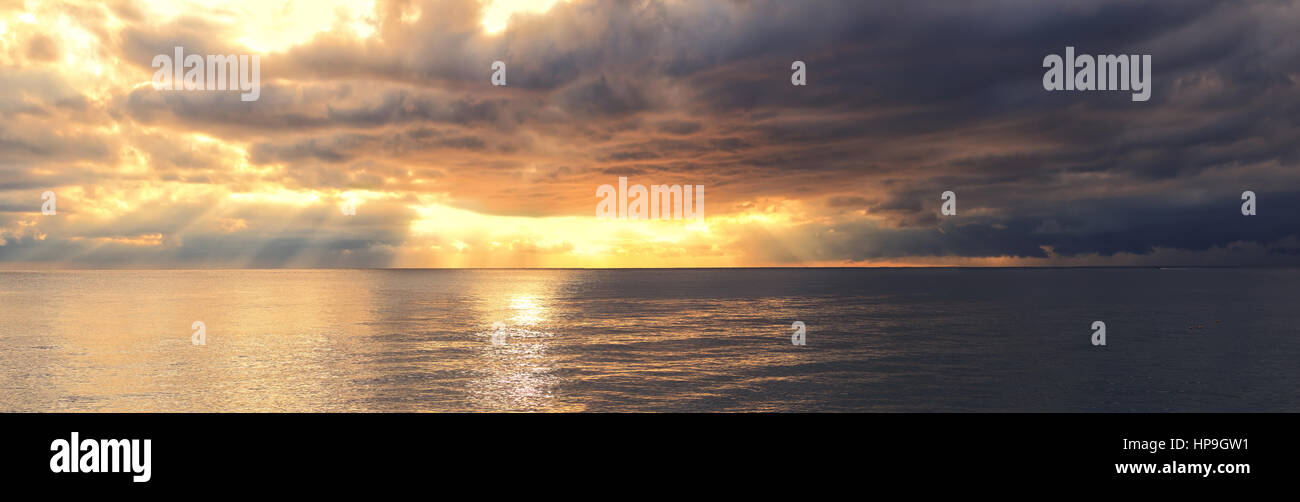 Tramonto luminoso con raggi di sole sopra il mare Foto Stock