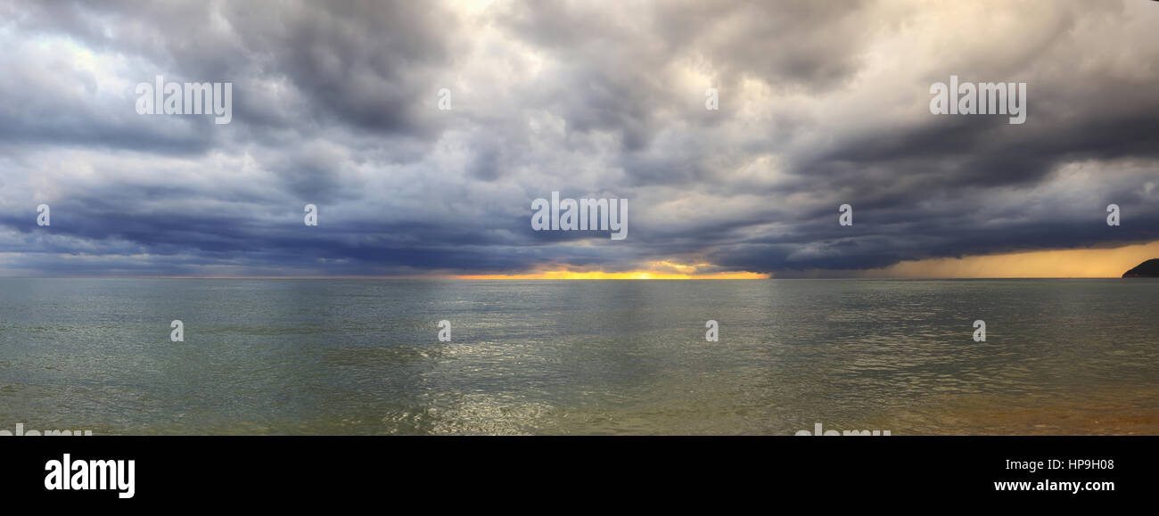 Nuvole di colore e luce del sole sopra il mare Foto Stock