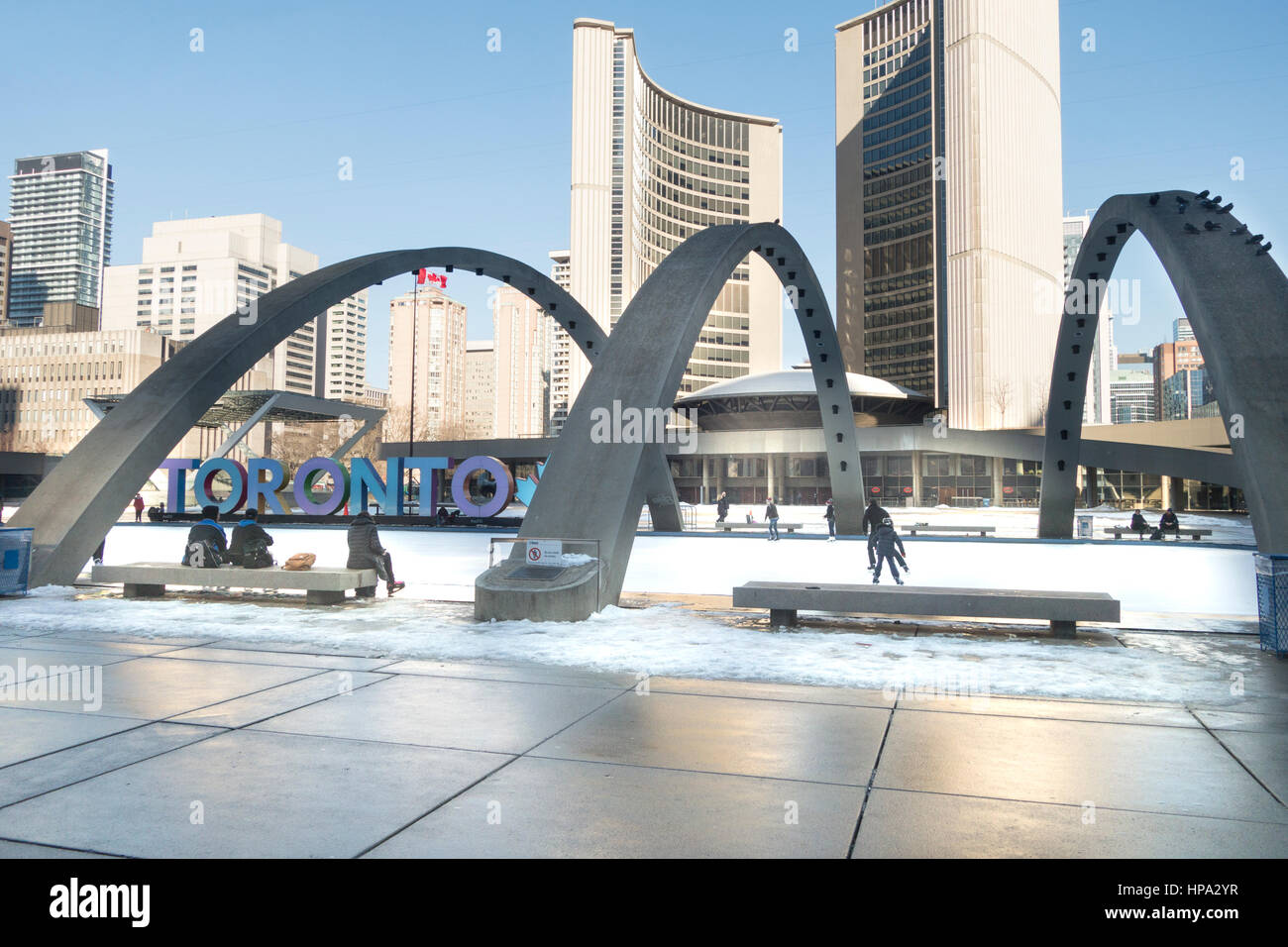 La gente di pattinaggio a Nathan Phillips Square a City Hall di Toronto, Ontario, Canada con Toronto segno tra gli archi Foto Stock
