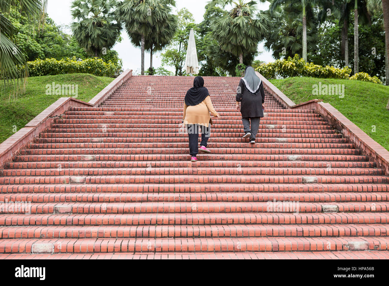 Due donne musulmane salire le scale per esercitare in un parco di Kuala Lumpur in Malesia. Foto Stock