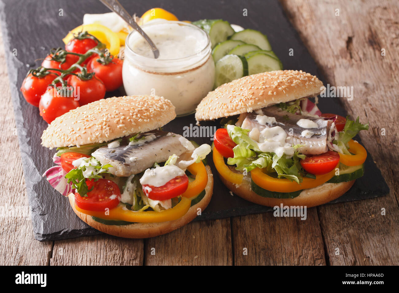 Sandwich con le aringhe marinate, con sugo di carne e verdura fresca su una tavola di close-up orizzontale. Foto Stock
