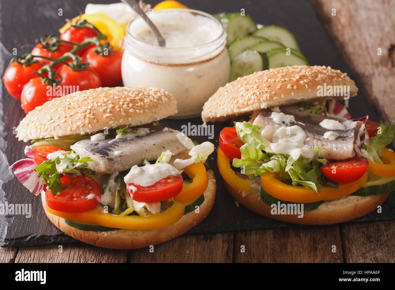 Gustoso panino con le aringhe, il sugo di pomodoro e verdure su una tabella di close-up orizzontale. Foto Stock