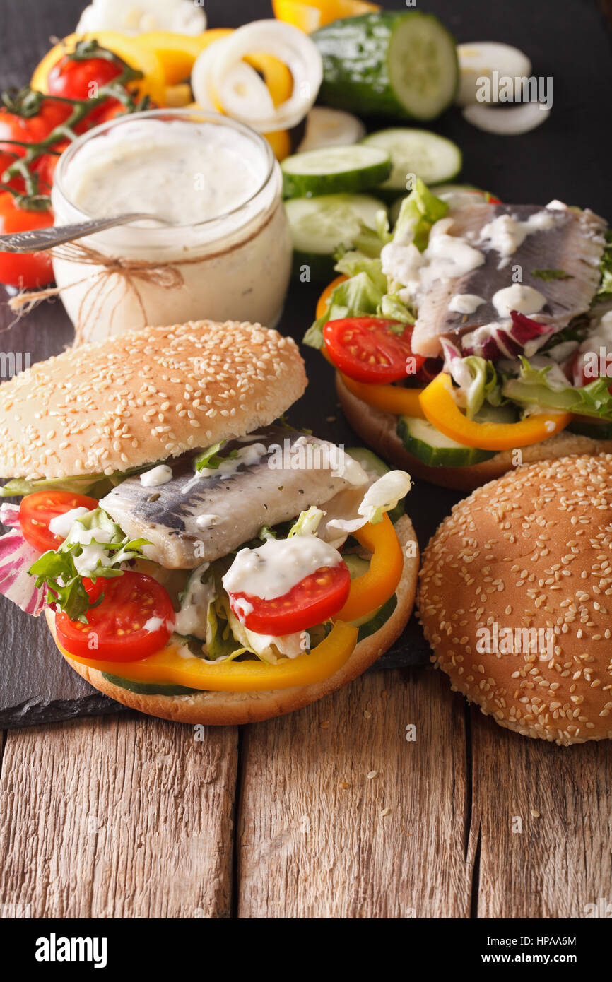 Aringa tedesco sandwich con salsa di pomodoro e verdure su una tabella di close-up verticale. Foto Stock
