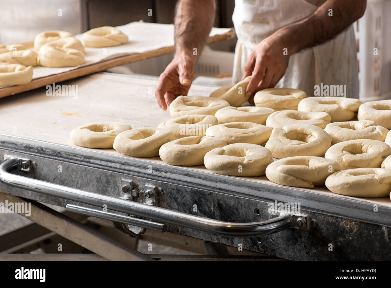 Close-up baker maschio mani rendendo frisella italiano ciambelle di pane, ponendo impasto crudo sulla tavola da forno Foto Stock