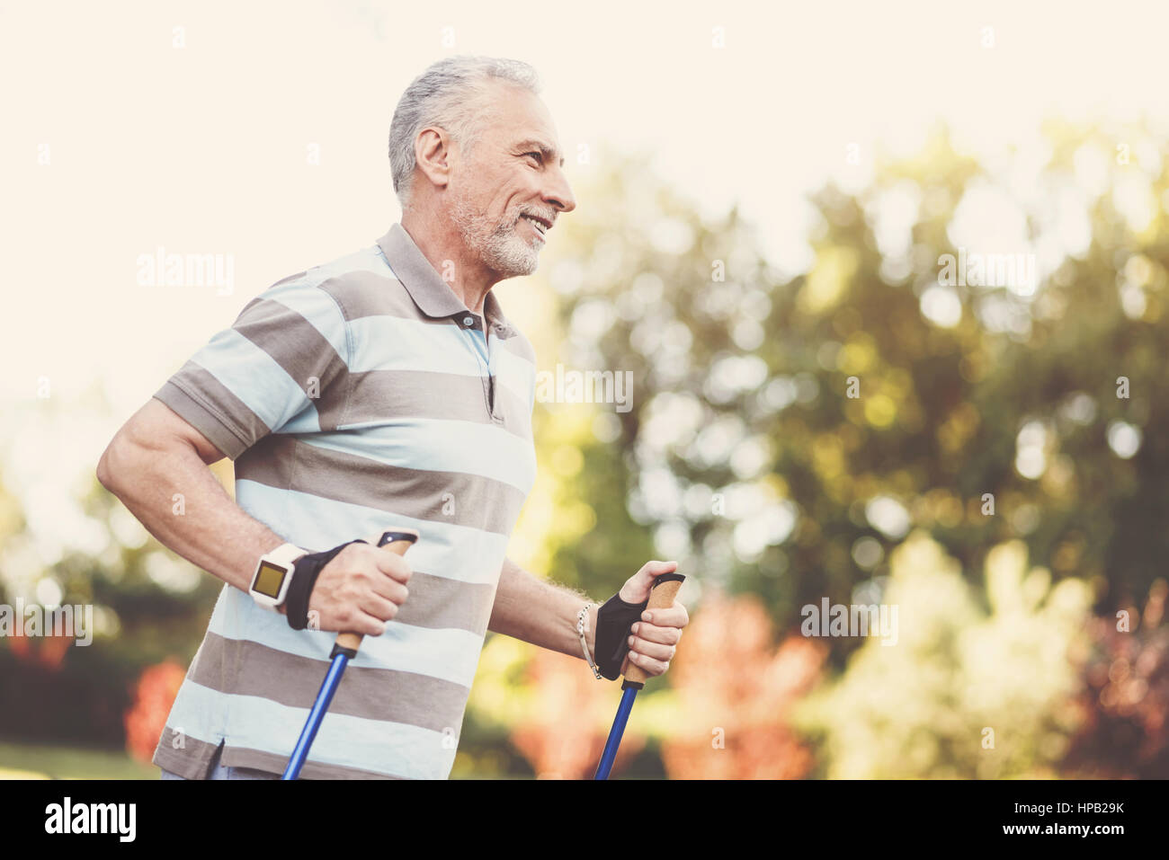 Mi piace lo sport. Allegro lieto uomo anziano sorridente e facendo qualche attività sportiva pur essendo al di fuori Foto Stock