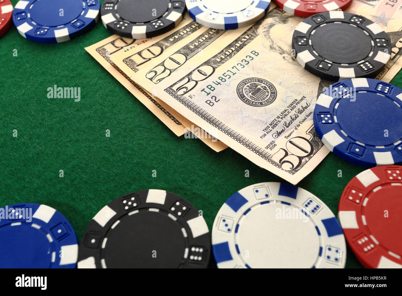 Poker chips e denaro vicino. Di dollari e trucioli sul green casino tabella closeup. Giochi di casinò dello sfondo. Foto Stock