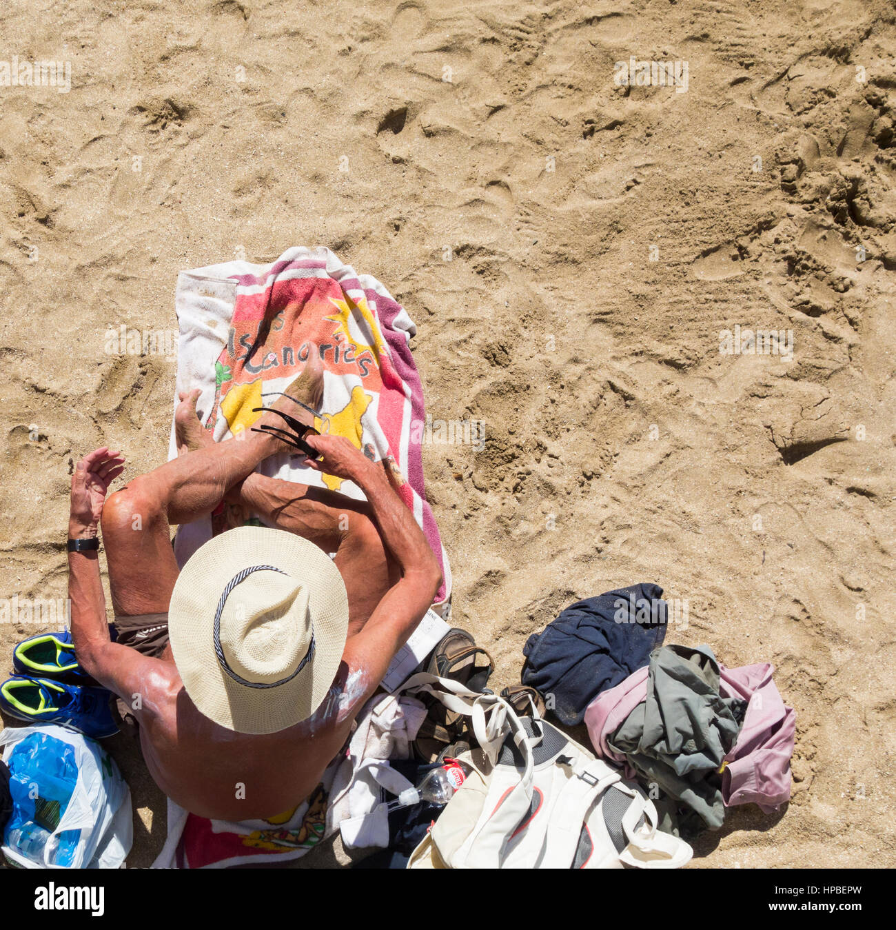 Alta Vista di uomo maturo con crema solare sulle spalle a prendere il sole sulla spiaggia in Spagna Foto Stock