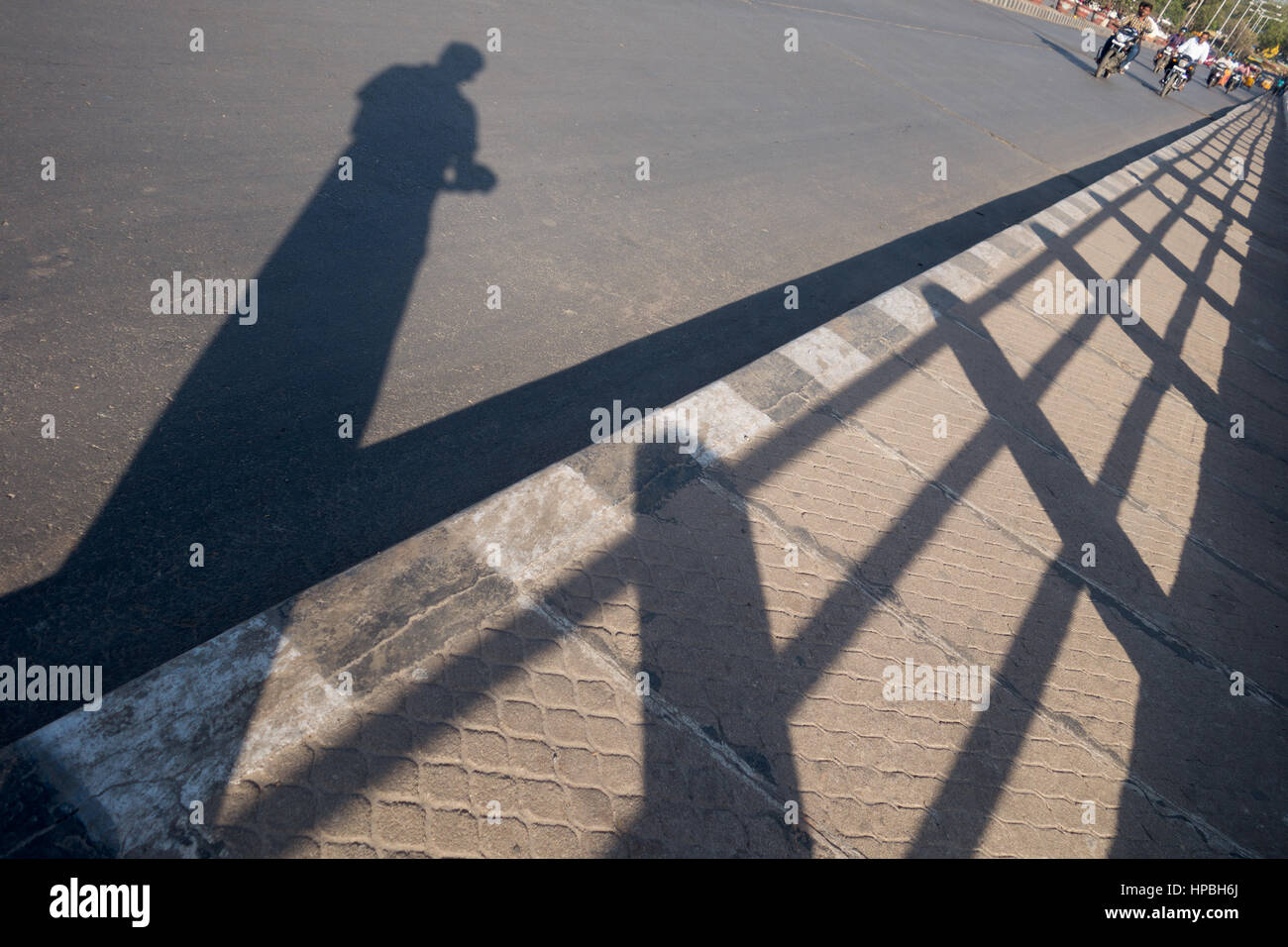 Uomo indiano di scattare una foto della propria ombra in piedi su un marciapiede accanto alla ringhiera in Hyderabad, India Foto Stock