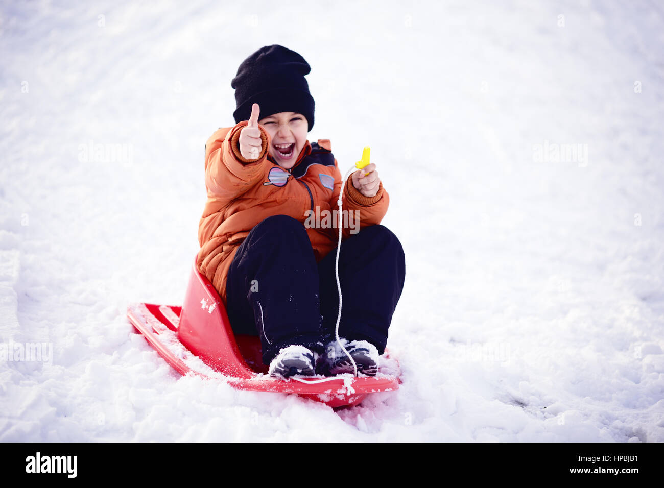 Bambino ragazzo dando Thumbs up, giocare e ridere sul nevoso inverno a piedi nella natura. Il gelo invernale. Foto Stock