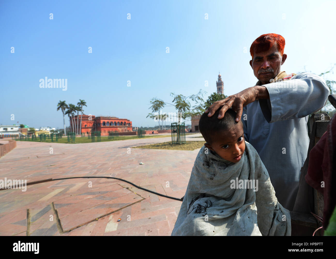 Un piccolo ragazzo di ottenere un taglio di capelli sulla strada Husanabad vicino alla vecchia torre dell orologio nella città di Lucknow. Foto Stock