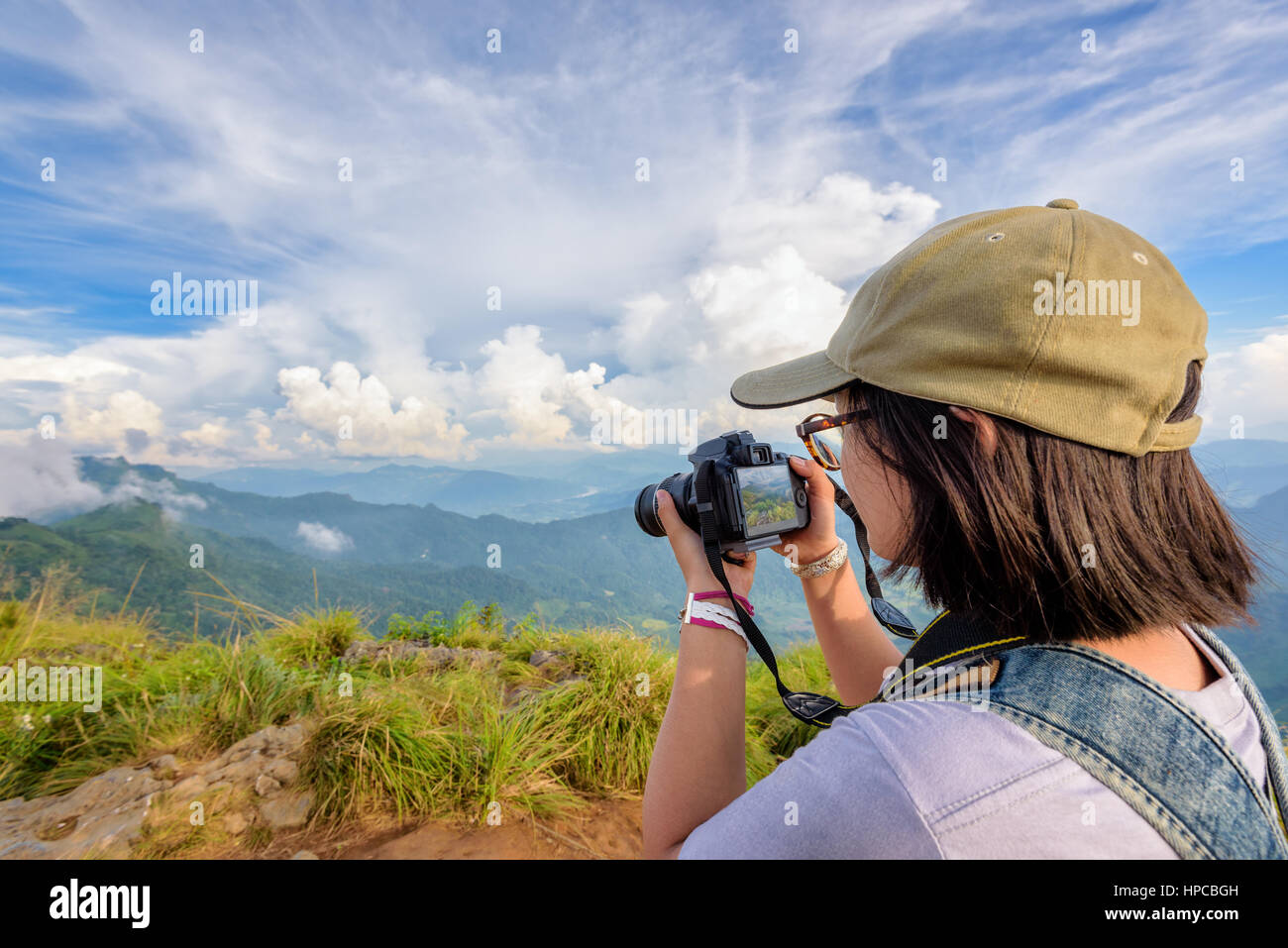 Escursionista asian teens ragazza con zaino cercando foto sulla fotocamera digitale è un bellissimo paesaggio naturale della sierra e cielo durante il tramonto sulla montagna Foto Stock