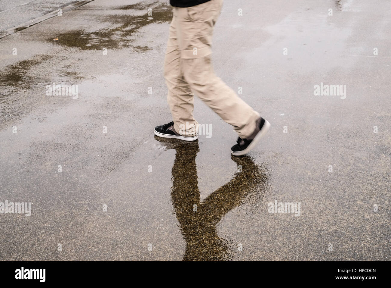 Un ragazzo a piedi sotto la pioggia Foto Stock