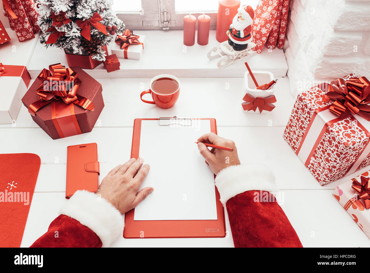 Babbo Natale a lavorare alla scrivania e scrivere su un foglio bianco su una clipboard, egli è sempre pronto per il Natale, il punto di vista shot Foto Stock