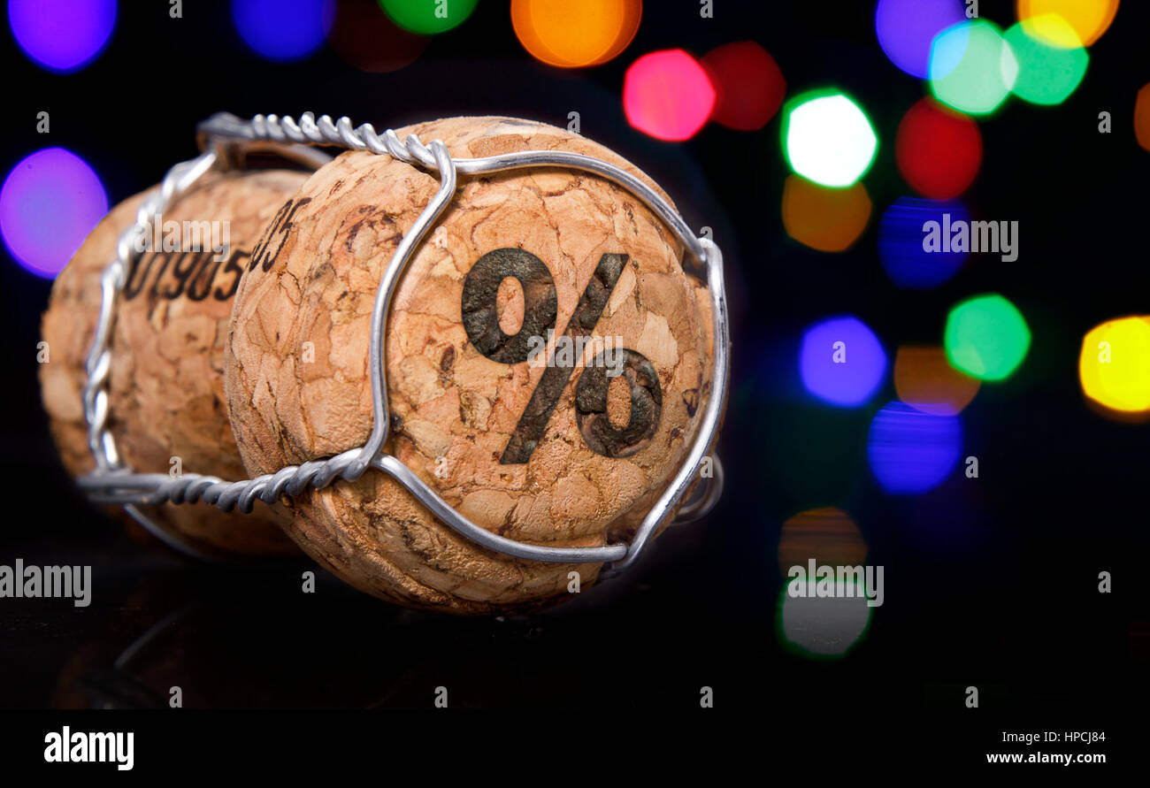 Tappo dello Champagne con la forma di un segno di percento bruciato in colorati e luci sfocate in background.(serie) Foto Stock