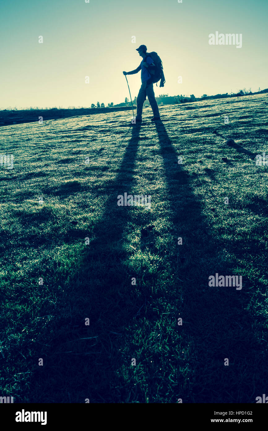 Escursionista maschio in retroilluminato mountais al tramonto. Foto Stock