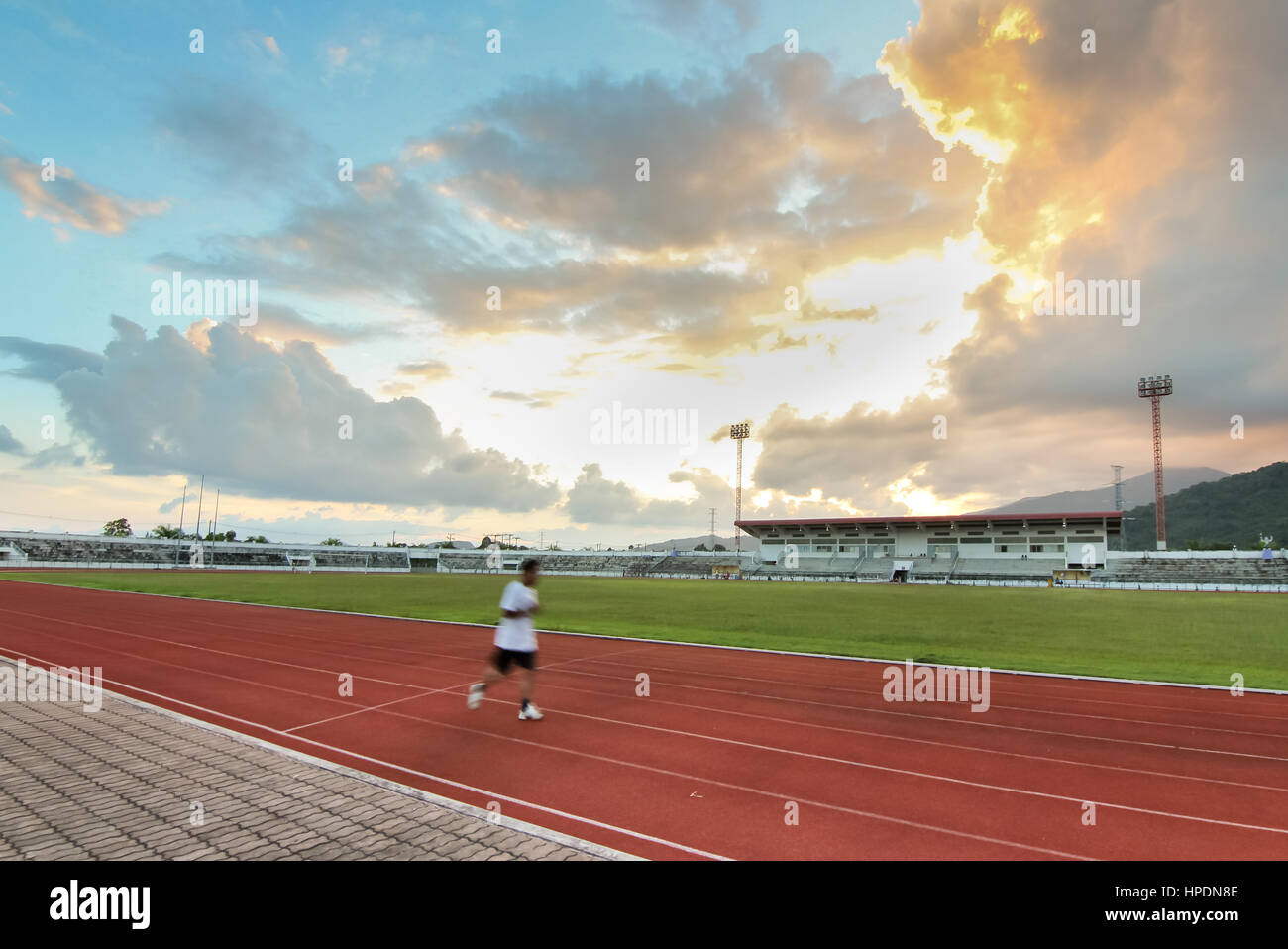 Uomo che corre nello stadio twilight tempo bello sfondo Foto Stock