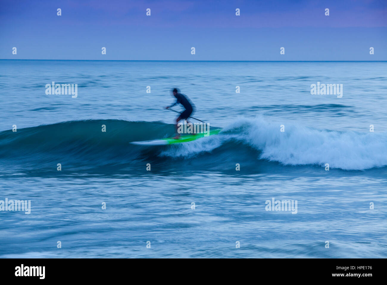 Stand up paddleboarder surf durante una nebbia tramonto a Hendry spiaggia di Santa Barbara in California Foto Stock