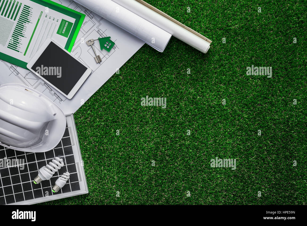 Progetto di casa, pannello solare e casco protettivo su erba verde, verde costruzione sostenibile e le energie alternative concept Foto Stock