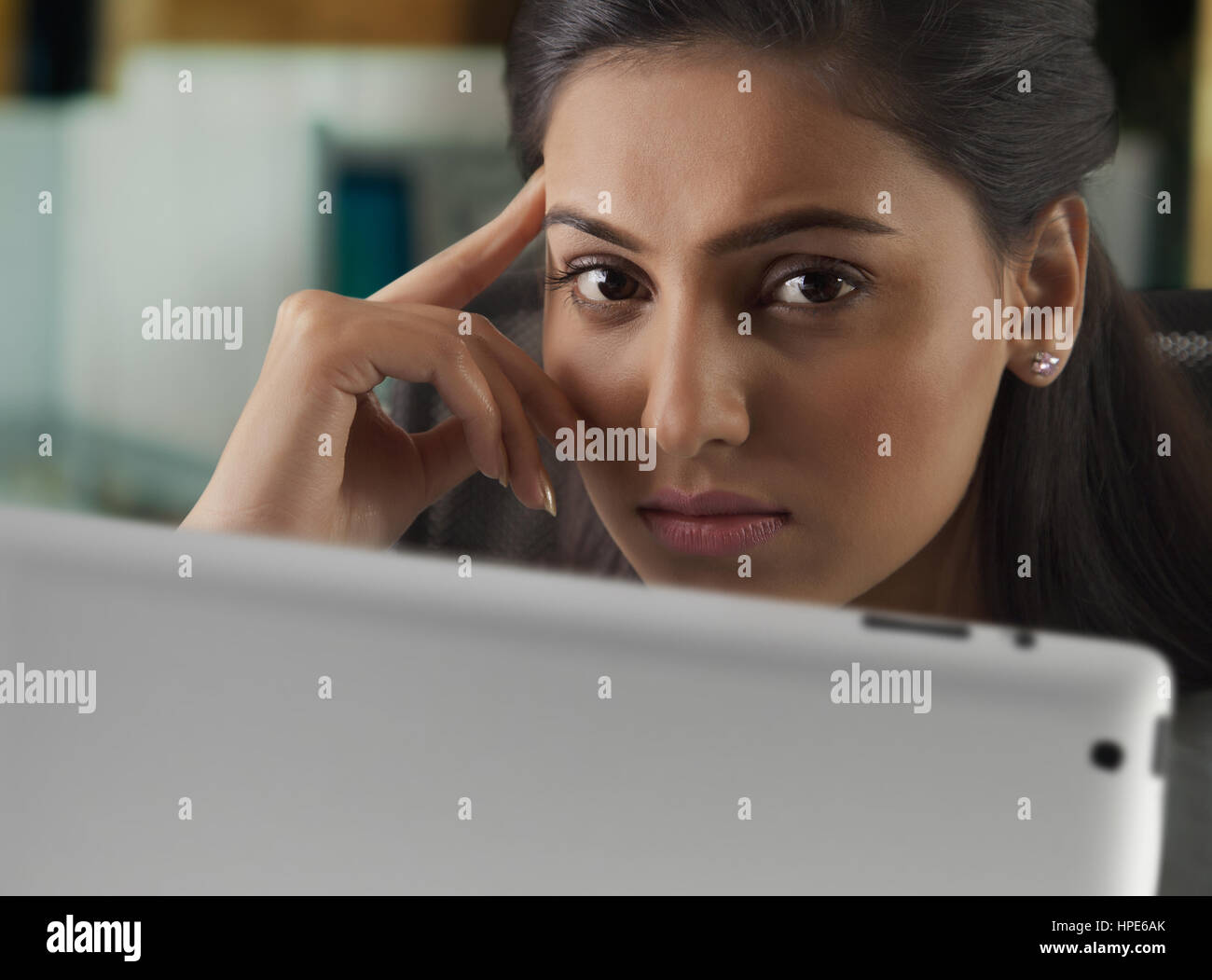 Close-up di imprenditrice con la sua mano sulla faccia usando tavoletta digitale alla scrivania in ufficio Foto Stock