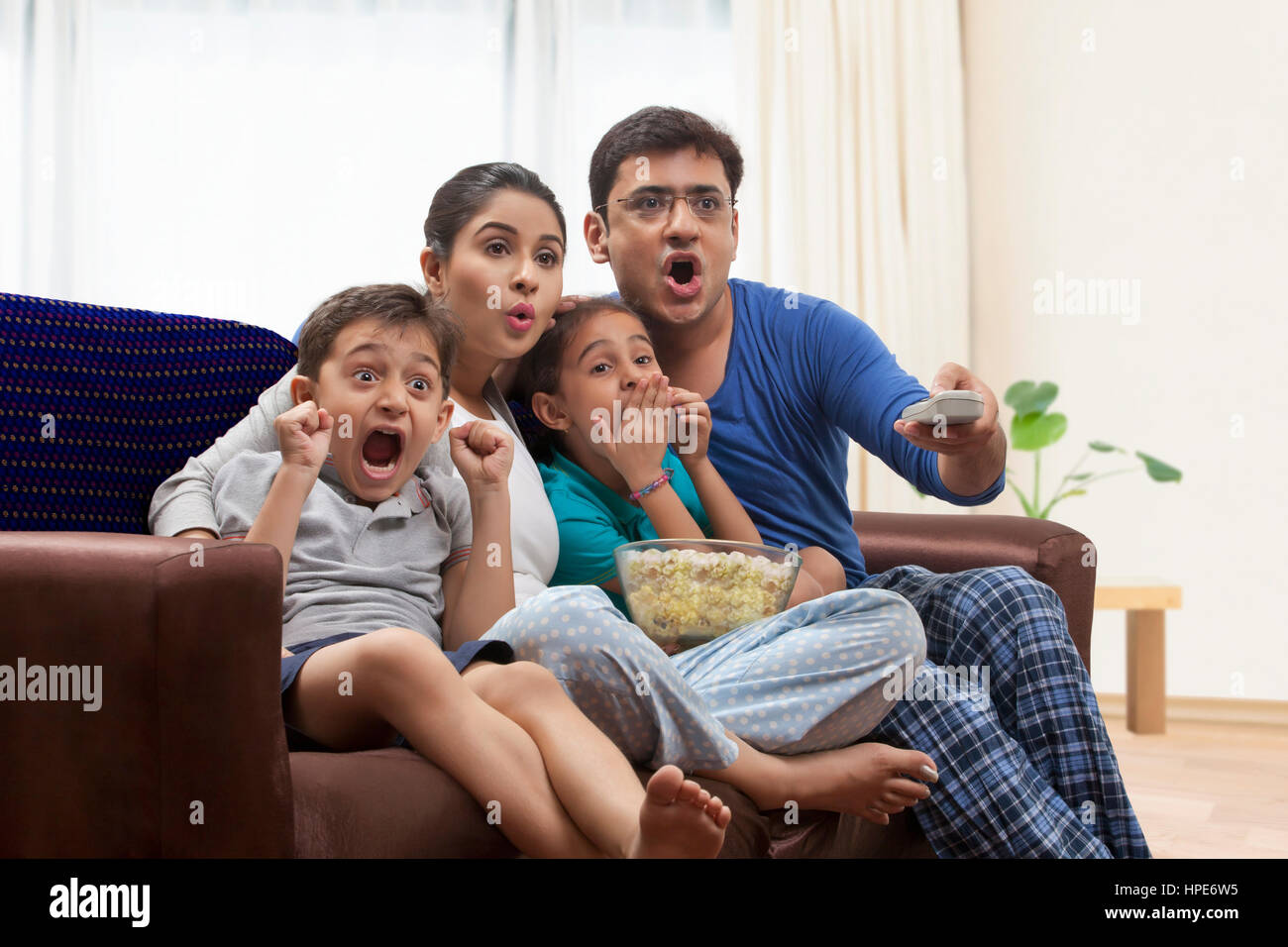 Famiglia in pigiama guardare la TV e mangiare popcorn Foto Stock