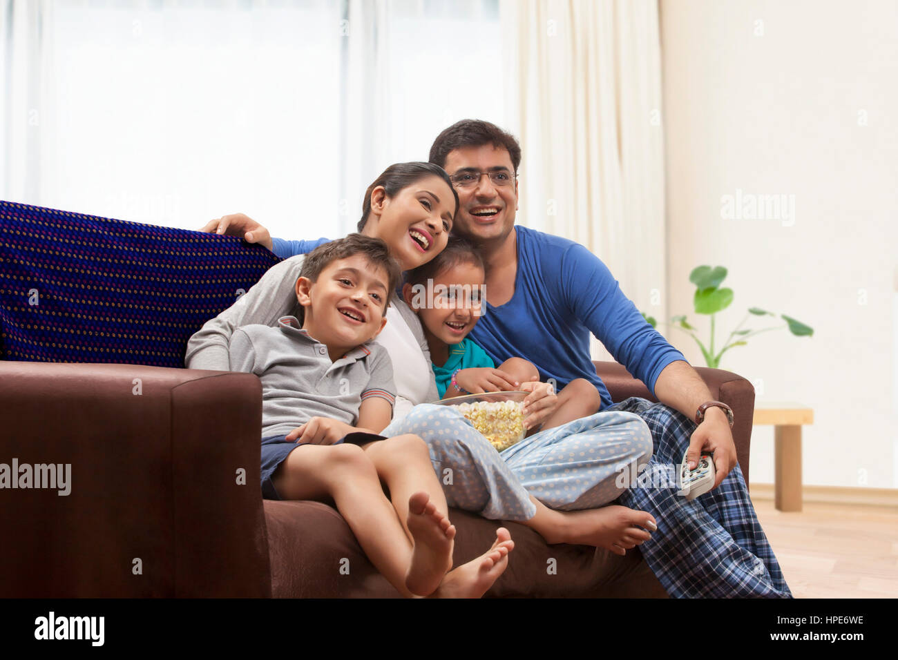 Famiglia in pigiama guardare la TV e mangiare popcorn Foto Stock