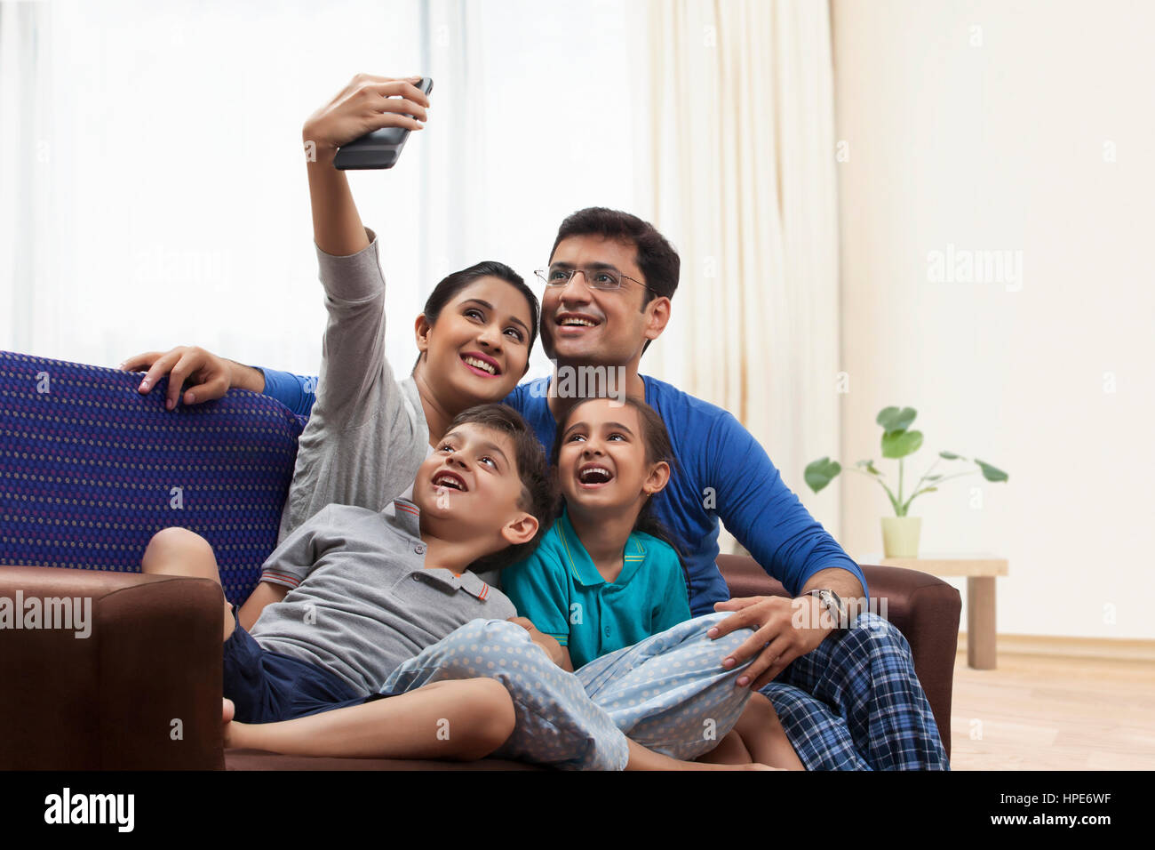 Famiglia in pigiama tenendo selfie sul divano Foto Stock
