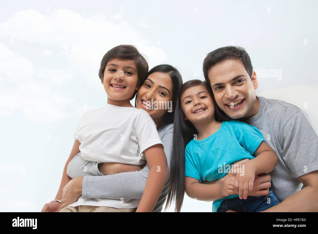 Ritratto di una famiglia felice guardando la telecamera contro il Cielo e nubi Foto Stock