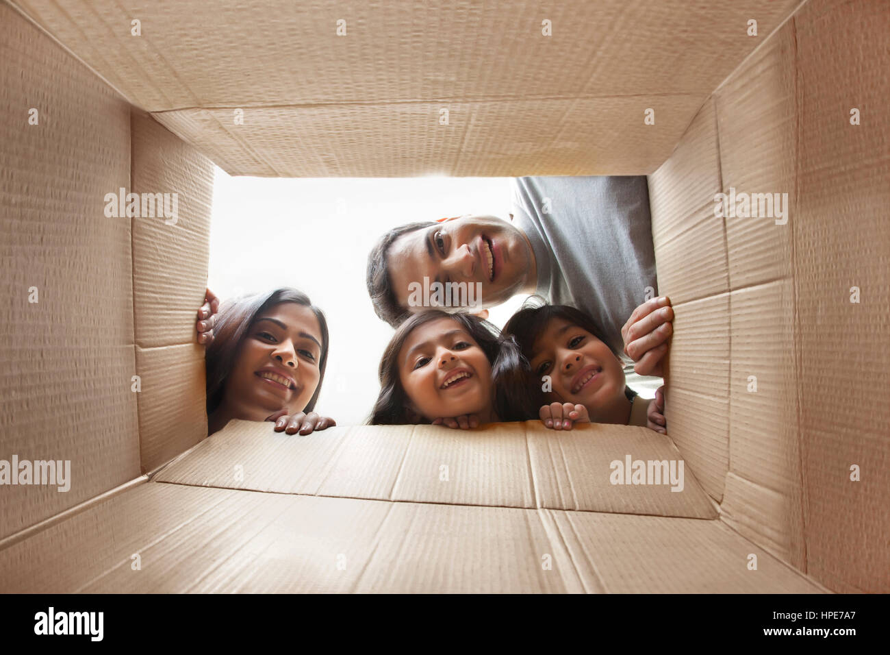 Famiglia guardando in giù a telecamera attraverso la scatola di cartone Foto Stock