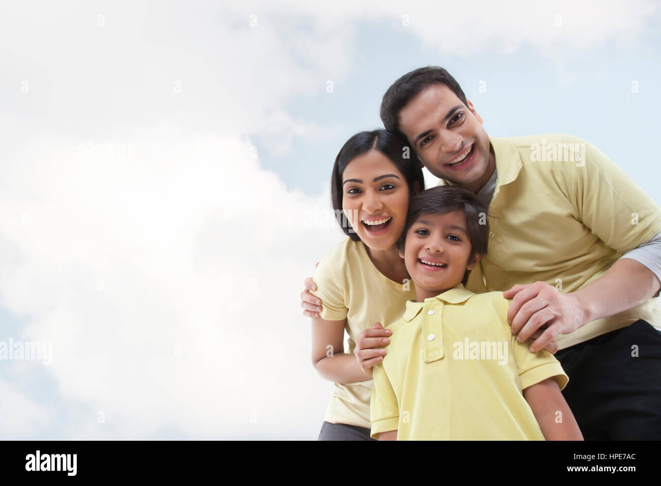 Ritratto di una famiglia felice guardando la telecamera contro il Cielo e nubi Foto Stock