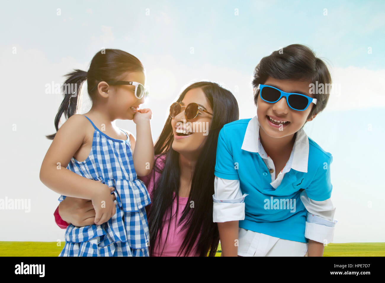 Famiglia sorridente indossando occhiali da sole divertimento in un parco sulla giornata di sole Foto Stock