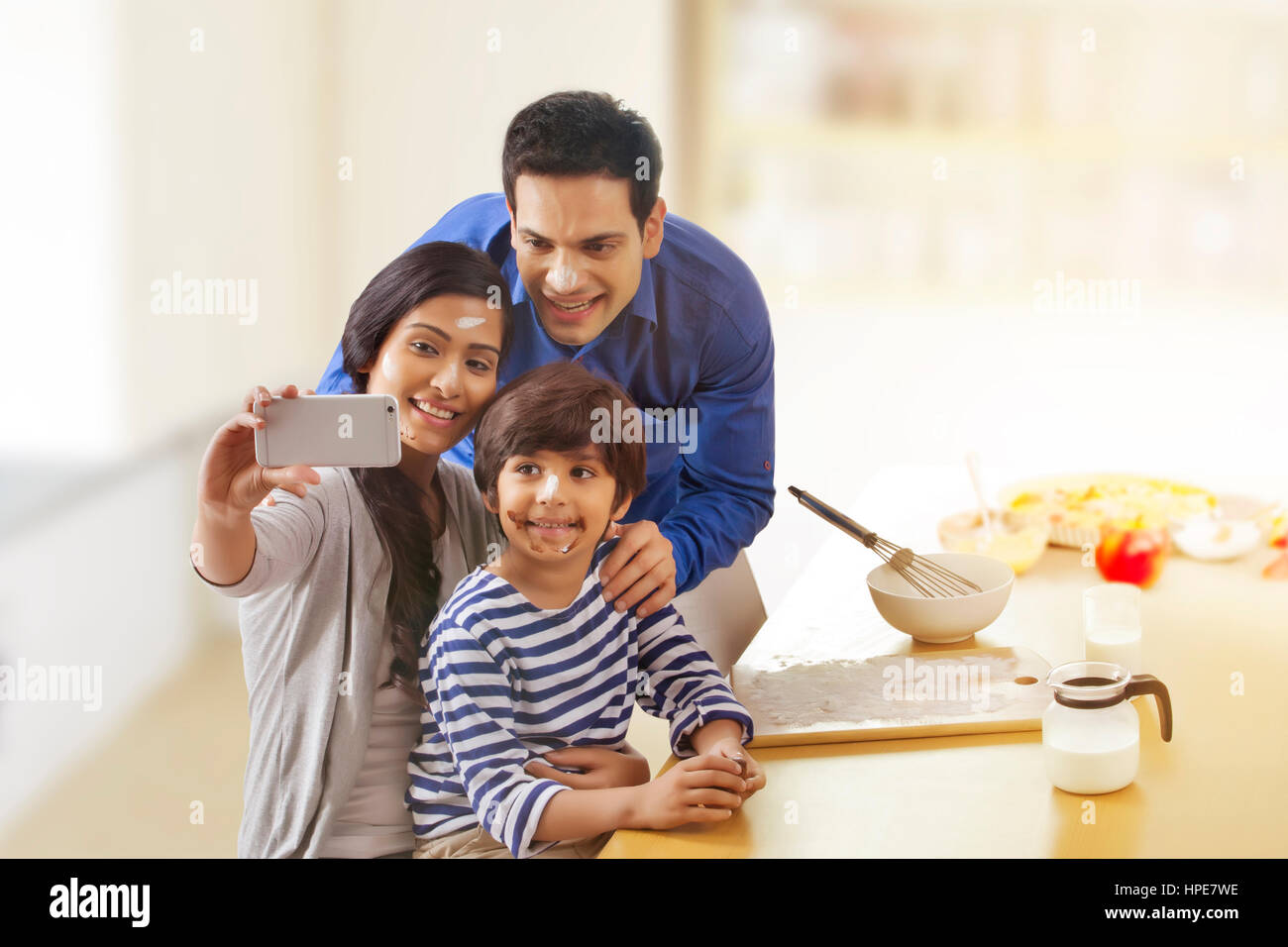 La famiglia felice tenendo selfie durante la cottura in cucina Foto Stock