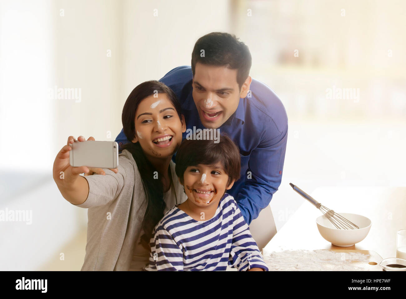 Famiglia tenendo selfie durante la cottura in cucina Foto Stock