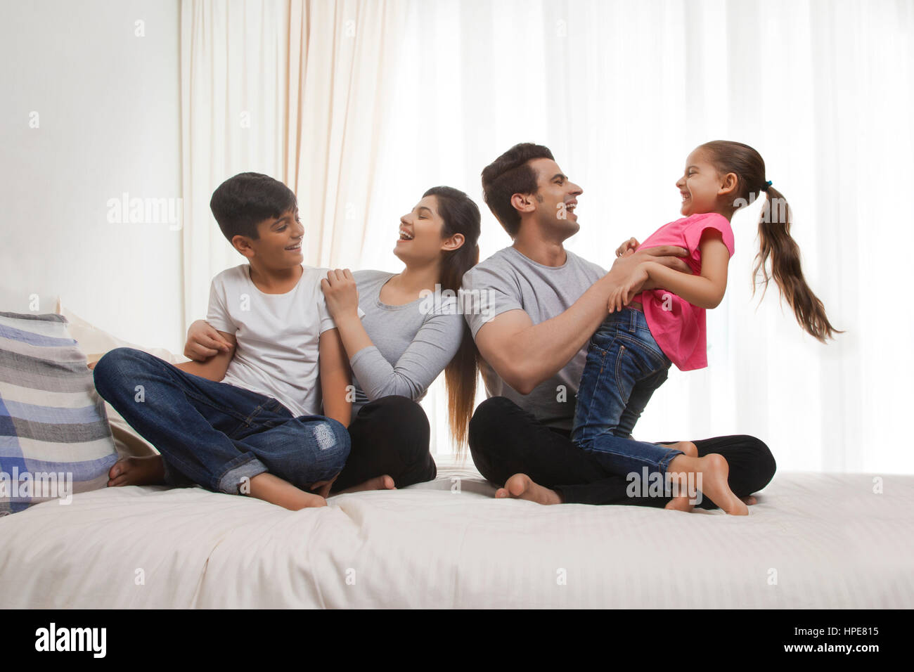 Famiglia con due bambini di ridere sul letto Foto Stock