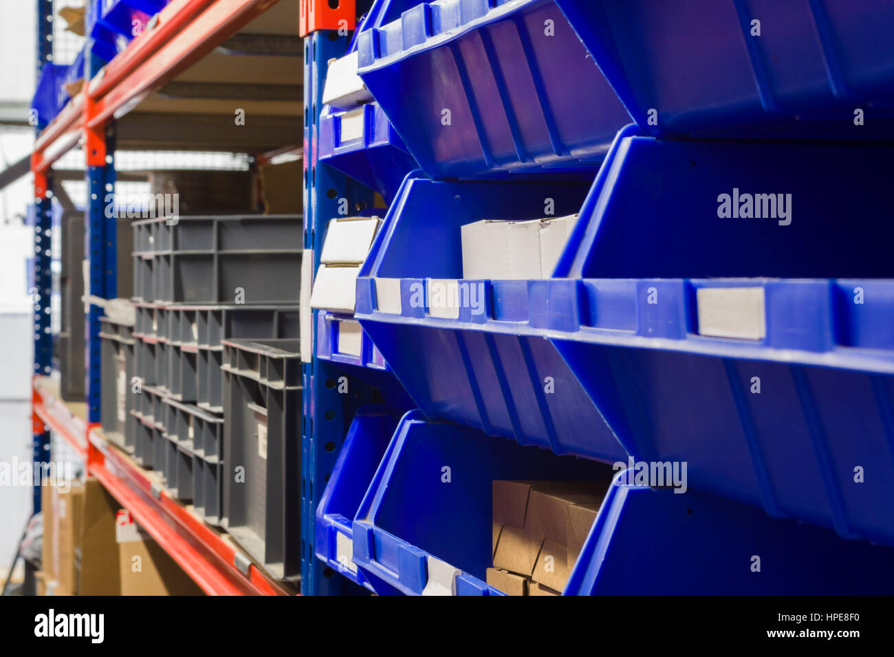 I contenitori di stoccaggio e industriali rack di stoccaggio in un magazzino shot con messa a fuoco poco profonda Foto Stock