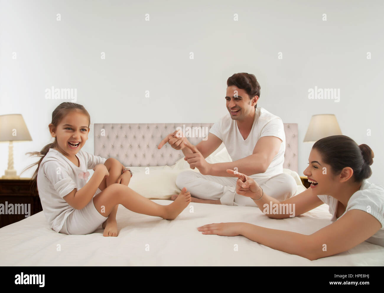 Famiglia giovane giocando sul letto con la loro figlia Foto Stock