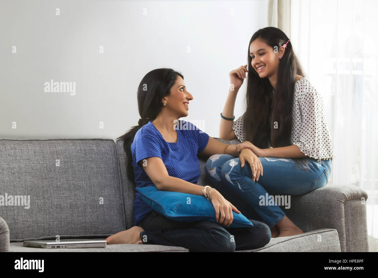 Sorridente madre e figlia adolescente conversare in salotto Foto Stock