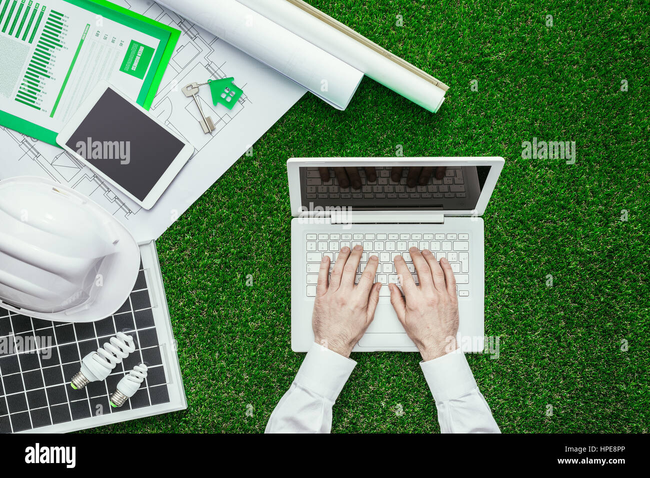 Progetto di casa, pannello solare, casco e ingegnere di lavoro con un laptop sull'erba verde edificio sostenibile e le energie alternative concept Foto Stock