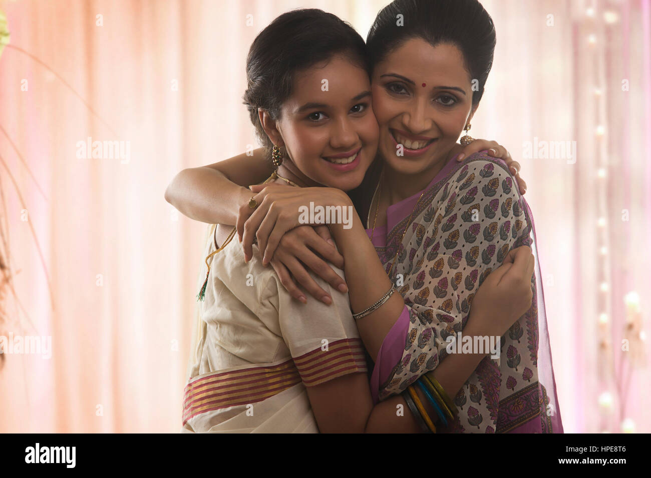 Sorridente figlia adolescente in sari abbracciando la madre Foto Stock