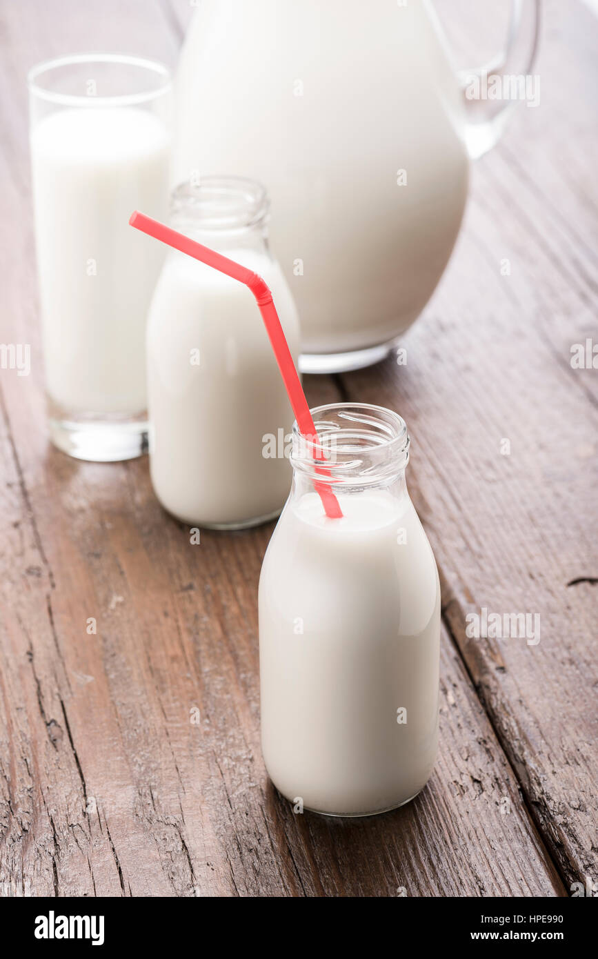 Bottiglia di latte con red cannuccia sul tavolo di legno Foto Stock