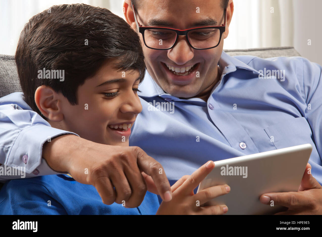 Sorridente padre e figlio guardando a tavoletta digitale Foto Stock