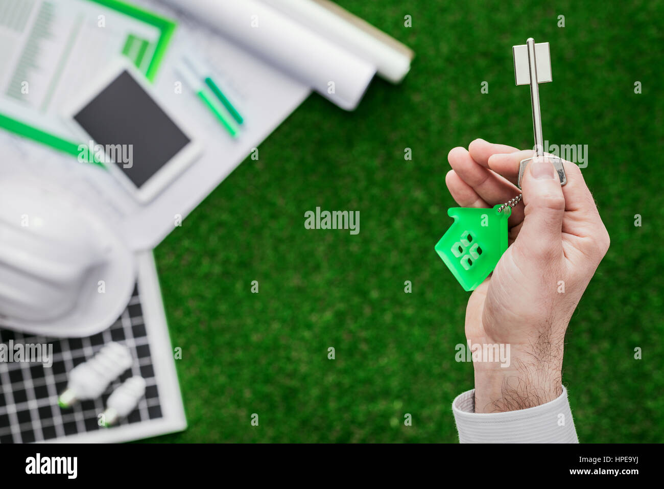 Agente immobiliare tenendo la vostra nuova casa tasti, pannello solare e bozze sullo sfondo, alloggiamento e green building concept Foto Stock
