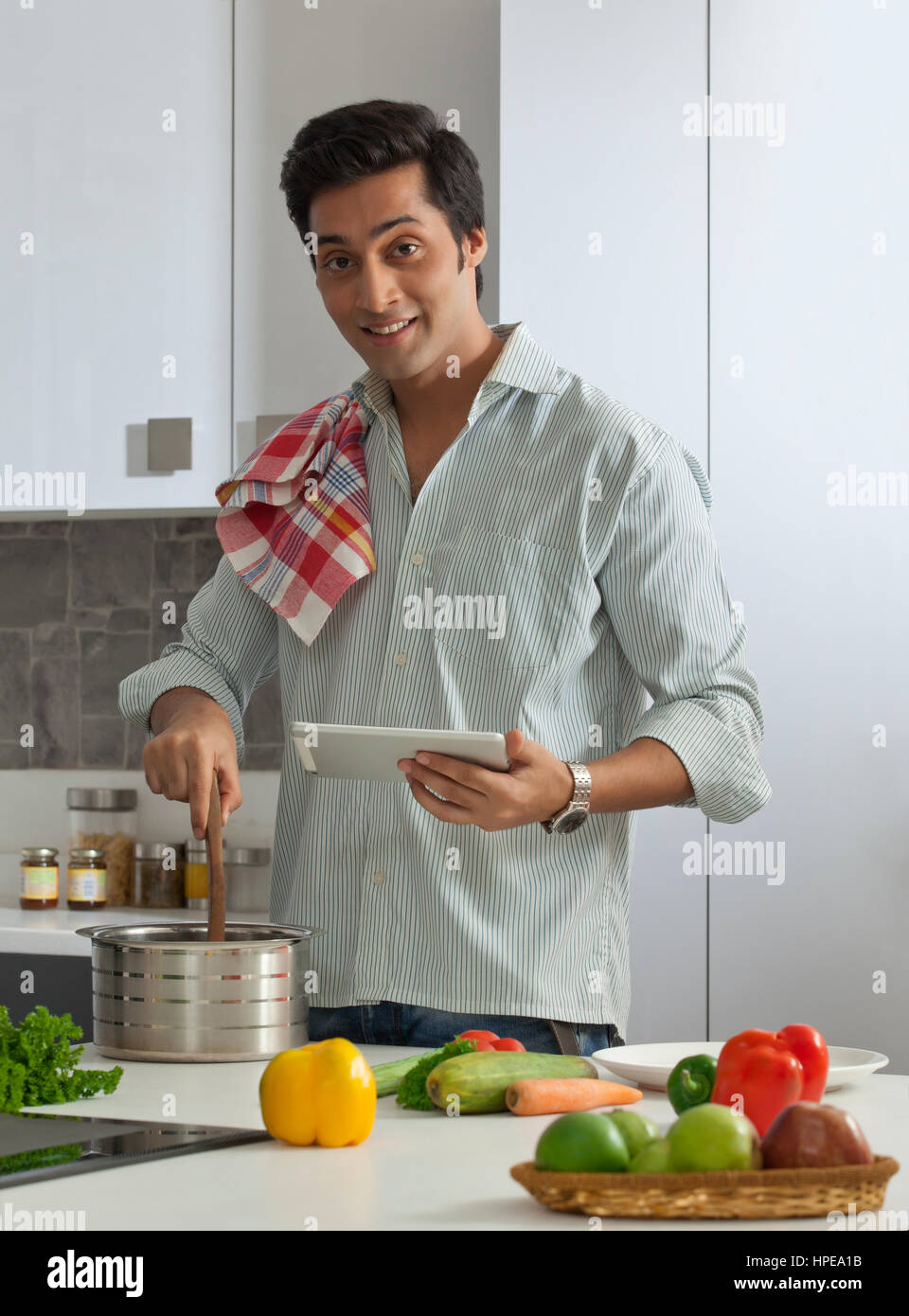 Uomo che utilizza una tavoletta digitale in cucina Foto Stock