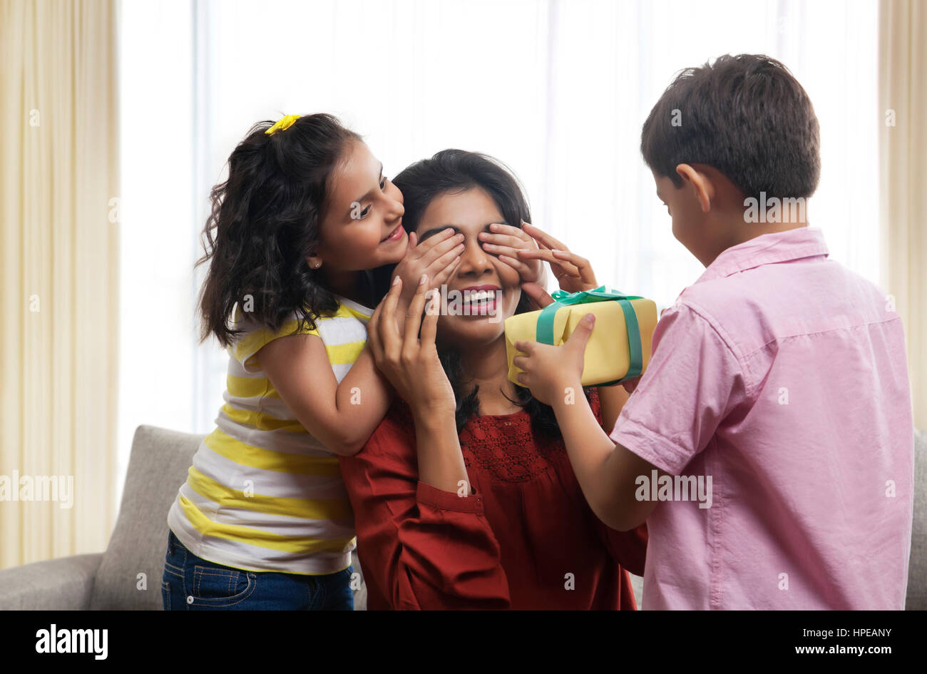 Due bambini presentando dono alla loro madre Foto Stock