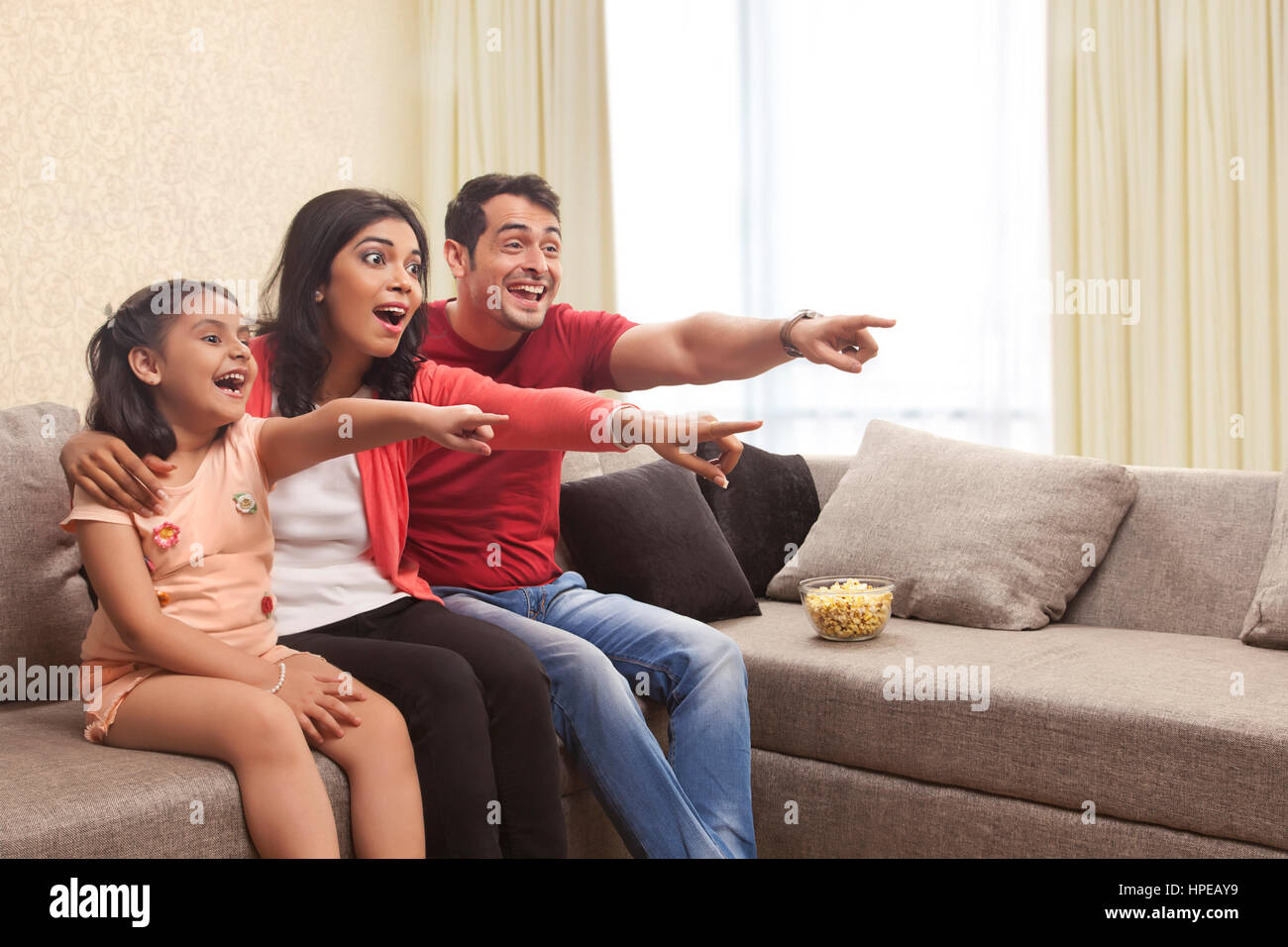 Famiglia seduti sul divano e puntando al televisore Foto Stock